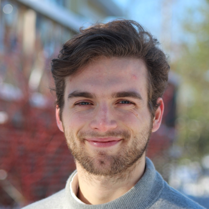 Go to top of page. The image is a headshot of Alexander Gower smiling against a snowy background